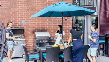 a group of people standing around a table under an umbrella